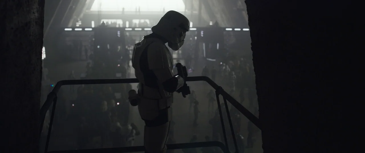 Solo: A Star Wars Story (2018) movie still: medium — A dark industrial metal platform overlooks a vast, hazy hangar filled with distant figures. A…