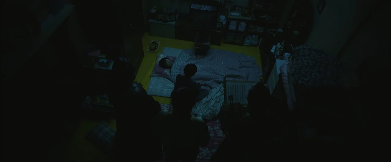 Along with the Gods: The Two Worlds (2017) movie still: wide — A dimly lit room contains a mattress on the floor with a person resting. Several…