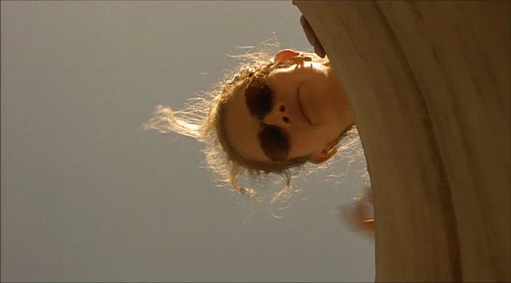Erin Brockovich (2000) movie still: closeup — A person looks down into the circular opening of a stone well. The bright sky forms the background…
