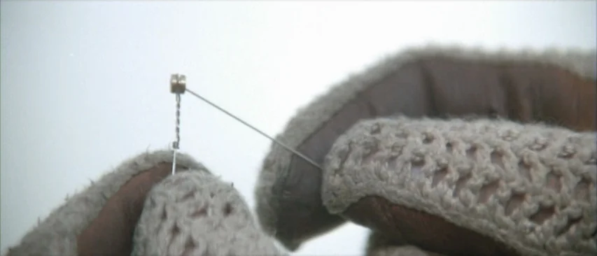 Roadgames (1981) movie still: closeup — Close-up shot of two gloved hands manipulating a small metallic component and wire. The background is a…