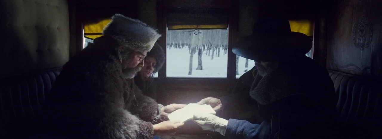 The Hateful Eight (2015) movie still: medium — The interior of a wooden stagecoach features leather-padded walls and a small rear window. Three…