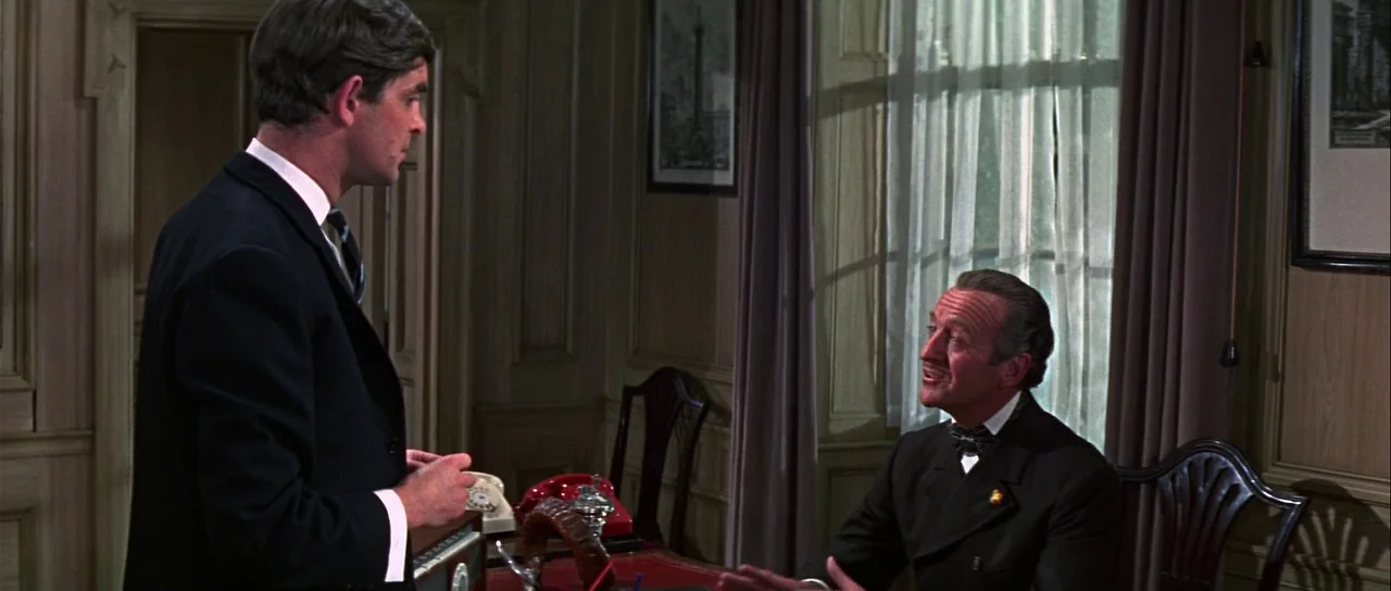 Casino Royale (1967) (1967) movie still: medium — A paneled study features a wooden desk with a red top and red telephone. A young man in a suit…