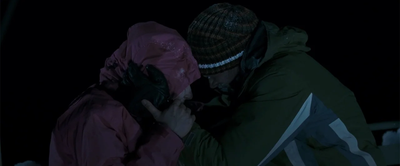 Frozen (2010) movie still: medium — A dark, snowy exterior environment at night under cold light conditions. Two people wearing winter gear stand…