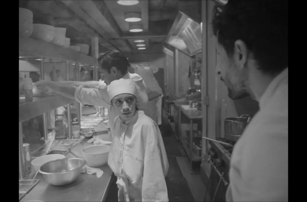 The Kitchen (2012) movie still: medium — A bustling professional kitchen features stainless steel prep counters and overhead industrial lighting. A…