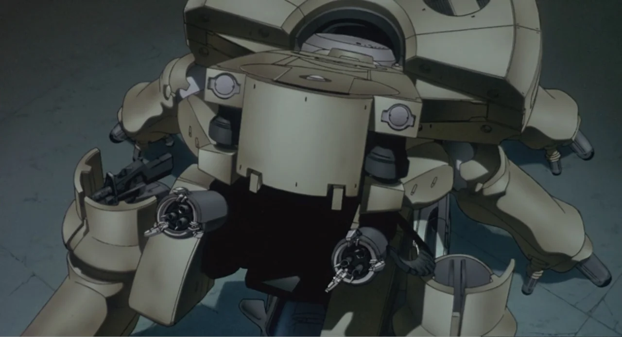 Ghost in the Shell (1995) movie still: medium — A tan, multi-legged mecha unit rests on a plain concrete floor in a hangar. Several mounted weaponry…
