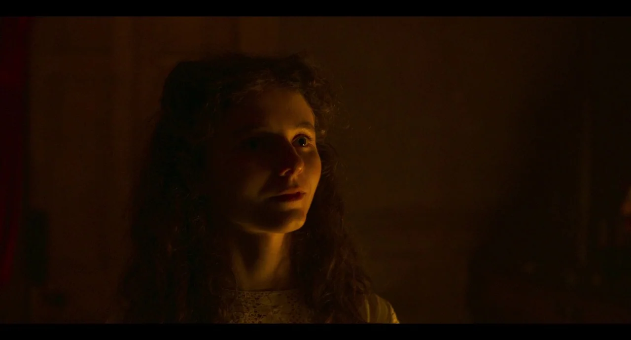 True History of the Kelly Gang (2019) movie still: closeup — A dark indoor space with minimal visibility of the background environment. A young…