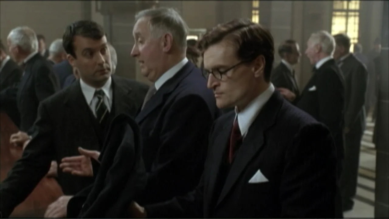 The Gathering Storm (2002) movie still: medium — A crowded 1940s building interior features men dressed in formal dark business suits. Three men…