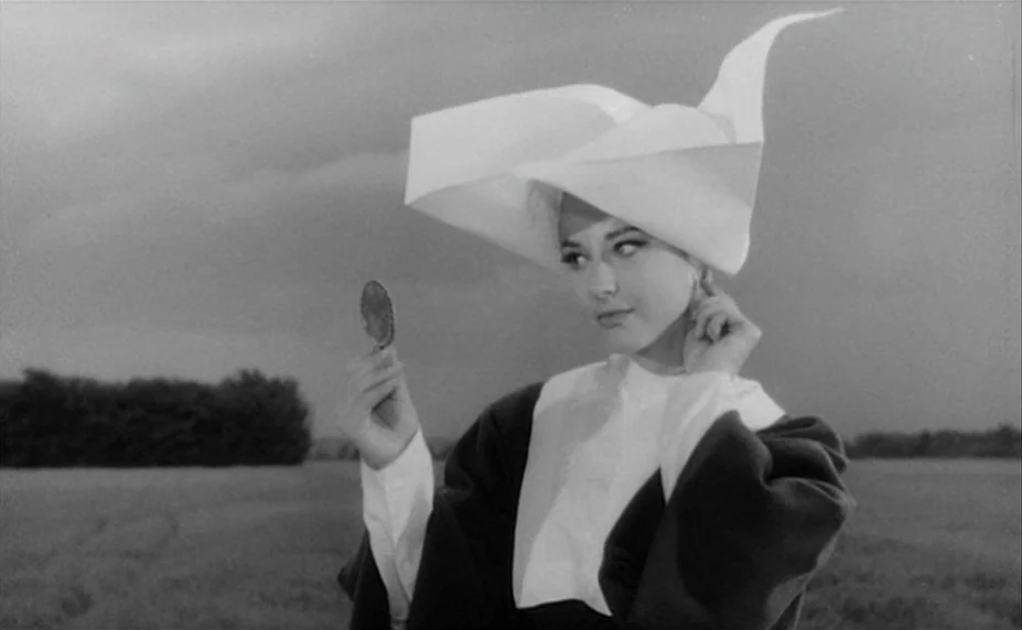 Judex (1966) movie still: medium — An open rural field under a cloudy, overcast sky provides an expansive backdrop. A woman dressed in a nun habit…