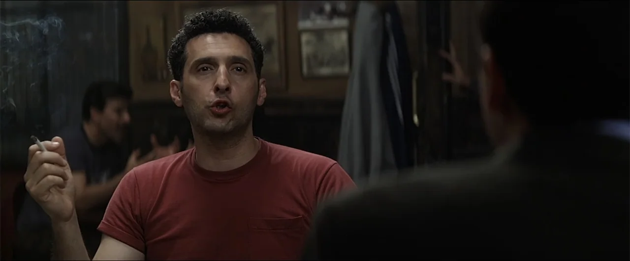Anger Management (2003) movie still: medium — A dimly lit bar interior contains dark wood panelling and framed pictures on walls. A man in a red…