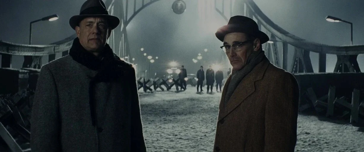 Bridge of Spies (2015) movie still: medium — A dark, snow-covered bridge serves as a crossing point between opposing military forces. Two men stand…