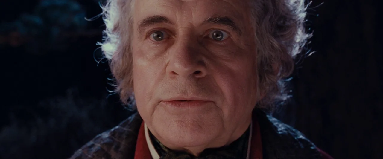 The Lord of the Rings: The Fellowship of the Ring (2001) movie still: closeup — An elderly man is framed in a dark, nocturnal woodland setting at…