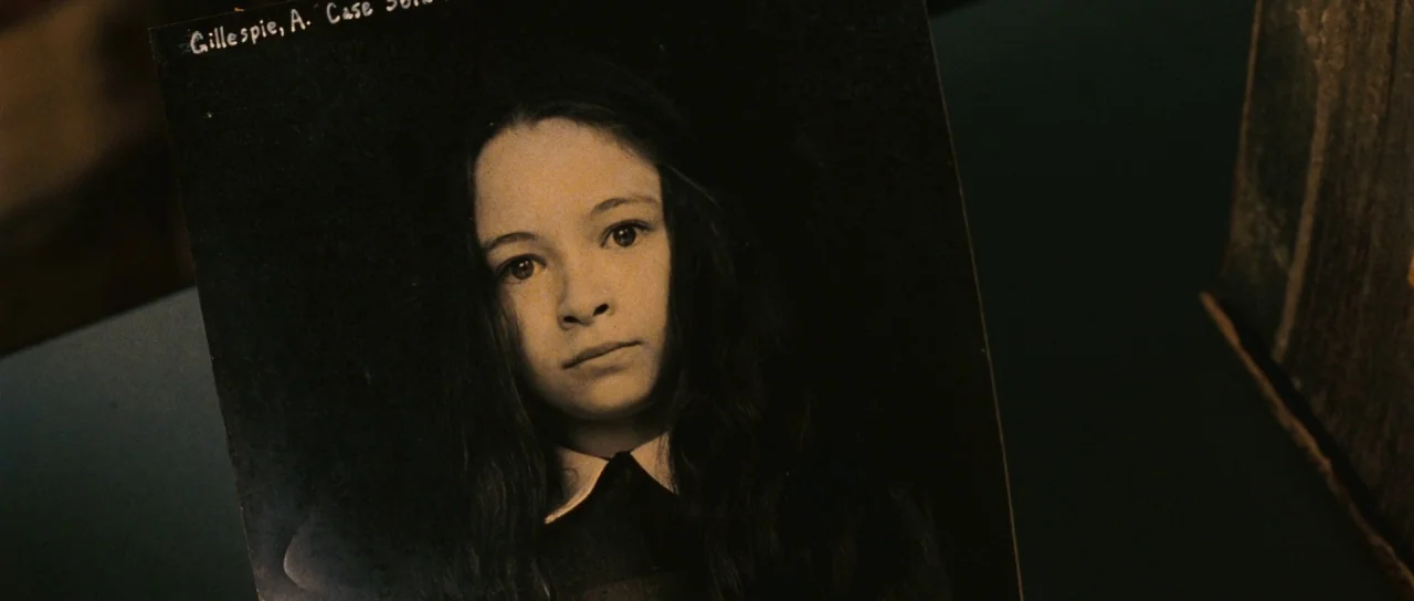 Silent Hill movie still: closeup — A close up of a vintage portrait photograph of a young girl. The photograph features handwritten white text at…