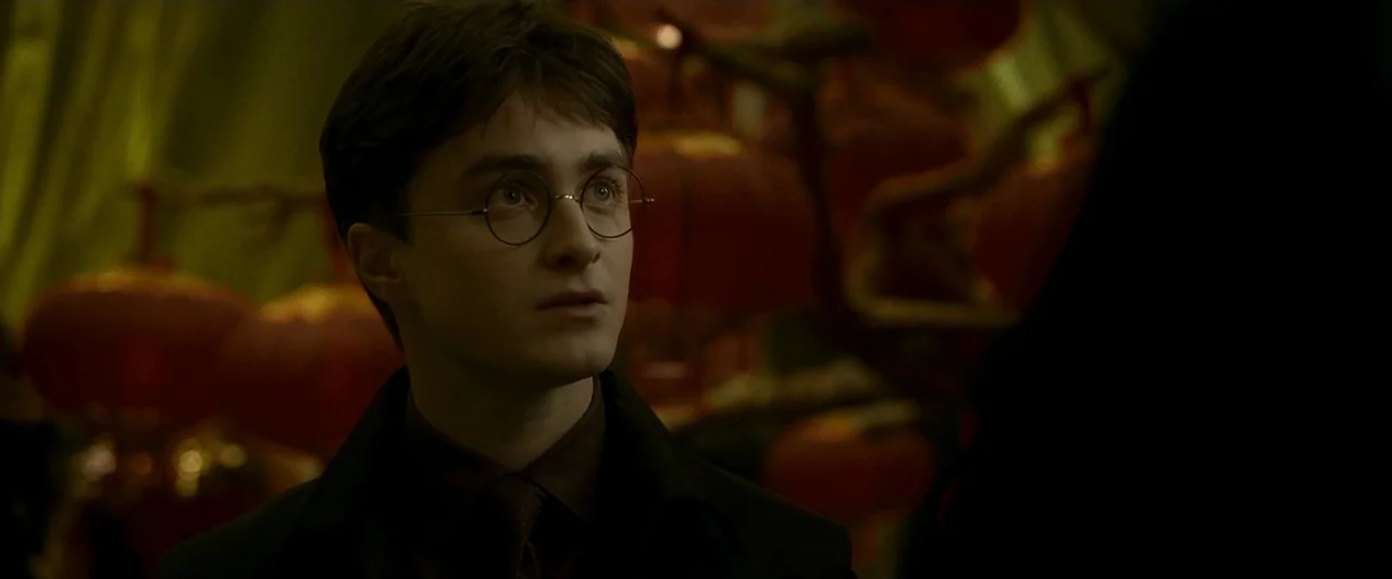Harry Potter & The Half Blood Prince (2009) movie still: closeup — A dimly lit restaurant space is decorated with multiple blurred red paper…