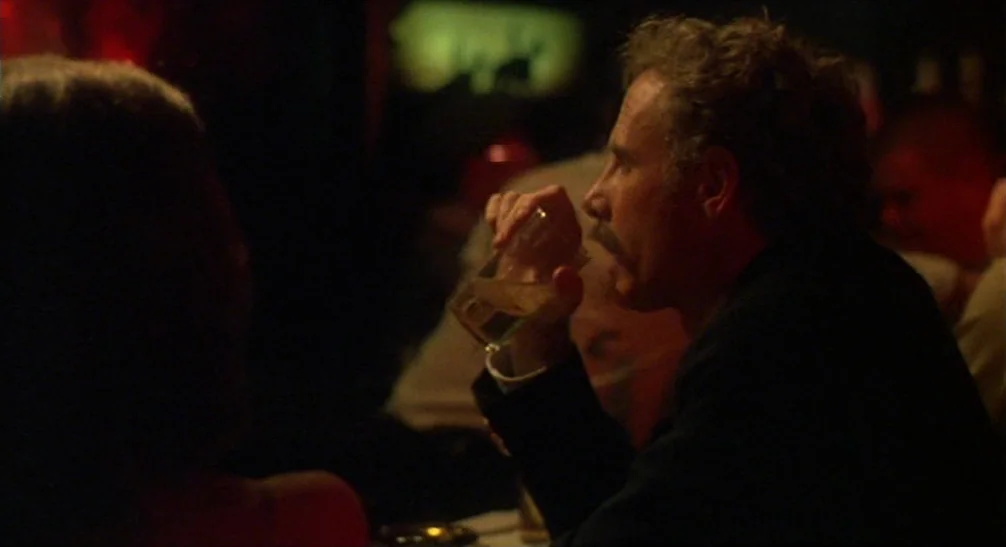 Coming Home (1978) movie still: medium — A dimly lit restaurant setting with blurred figures in the background and foreground. A man sits at a table…