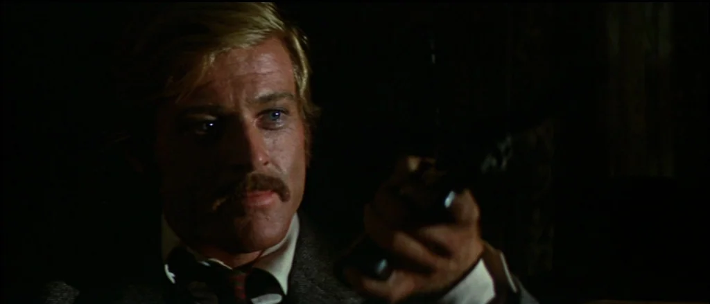 Butch Cassidy and the Sundance Kid (1969) movie still: closeup — A dark, dimly lit indoor space with textured wall patterns visible in the gloom. A…
