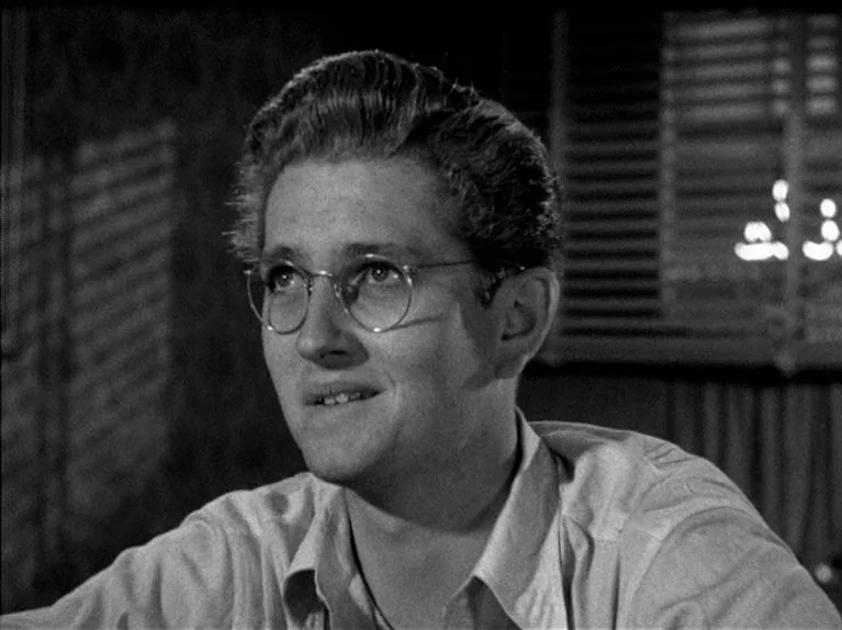 The Big Night (1951) movie still: closeup — An interior space with window blinds visible in the background against a dark wall. A young man with…