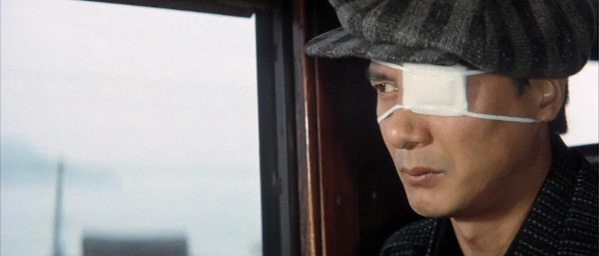 The Horrors of Malformed Men (1969) movie still: closeup — A man sits inside a wooden compartment with a window looking out onto water. The man…