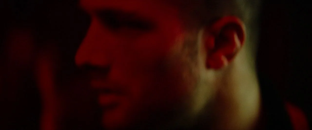 Calm With Horses (2019) movie still: closeup — A man's face is shown in profile within a dark environment. Intense red light highlights his skin and…