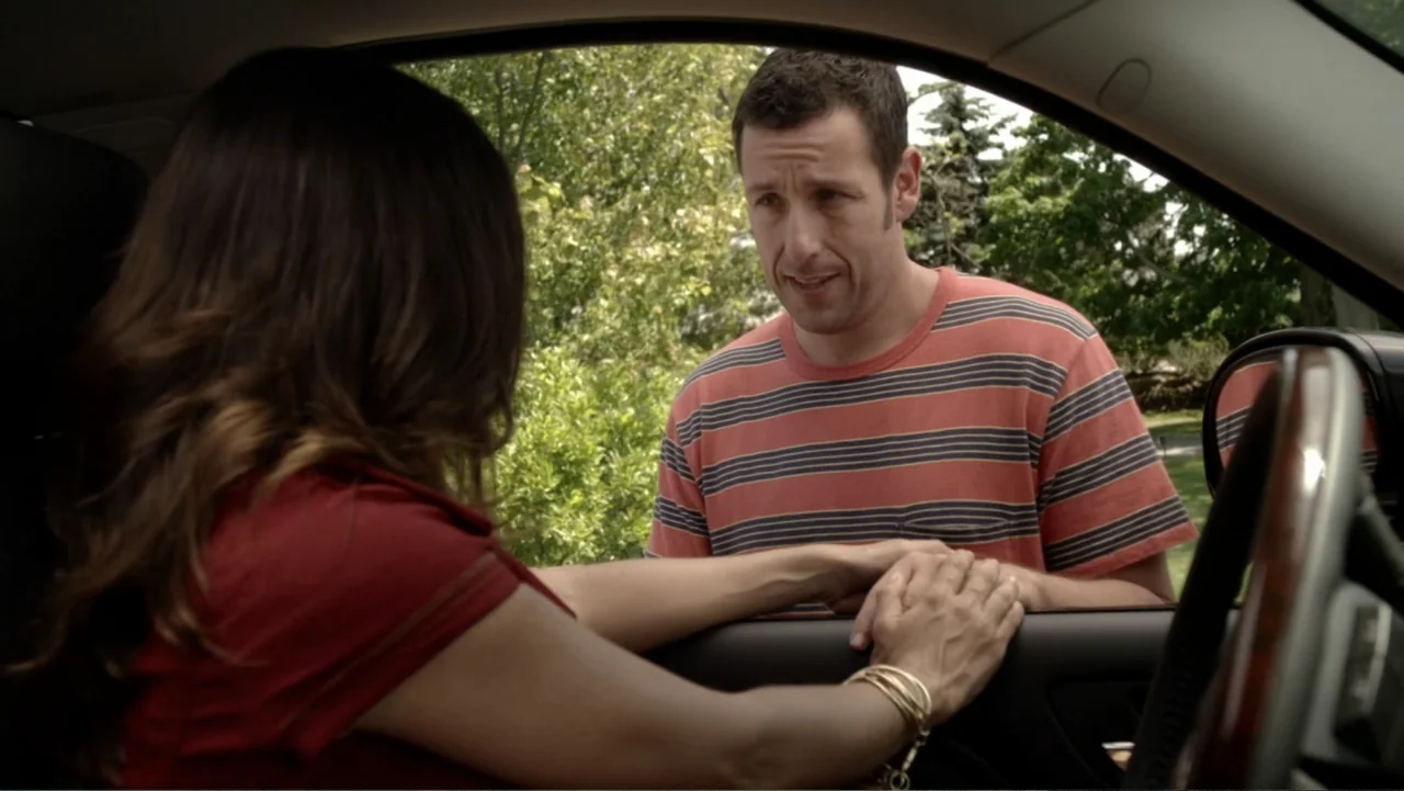 Grown Ups 2 (2013) movie still: medium — A man stands outside a car, speaking to a woman sitting inside the vehicle. The woman reaches out from the…