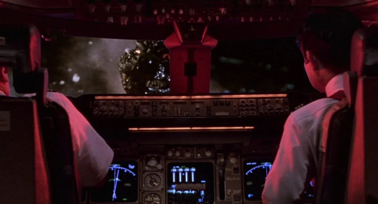 Godzilla vs. Destoroyah (1995) movie still: wide — The cockpit of a commercial aircraft at night features rows of glowing flight controls. Outside…