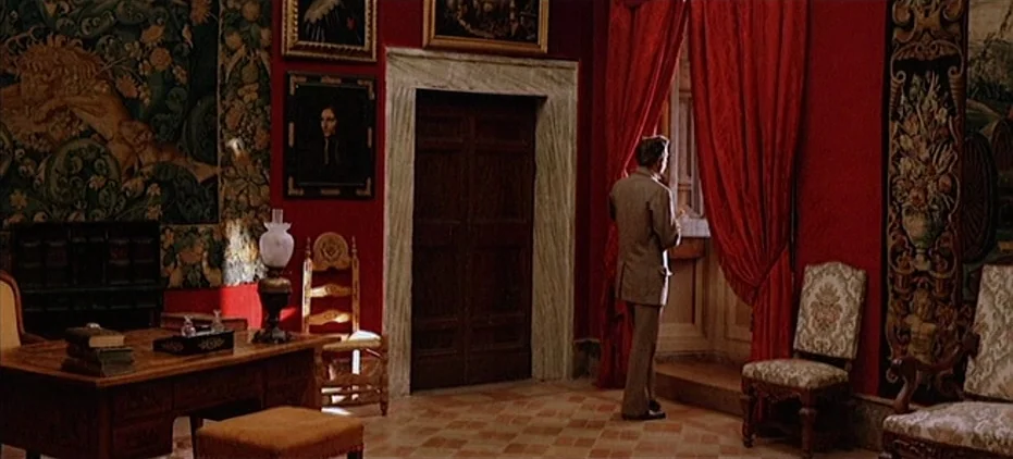 The Leopard (1963) movie still: wide — A study with deep red walls features heavy velvet curtains and antique wooden furniture. A man in a suit…