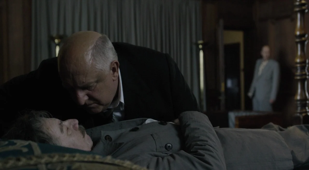 The Death of Stalin (2017) movie still: medium — A dark hotel room with wood paneled walls and draped curtains in the background. A heavy-set man…