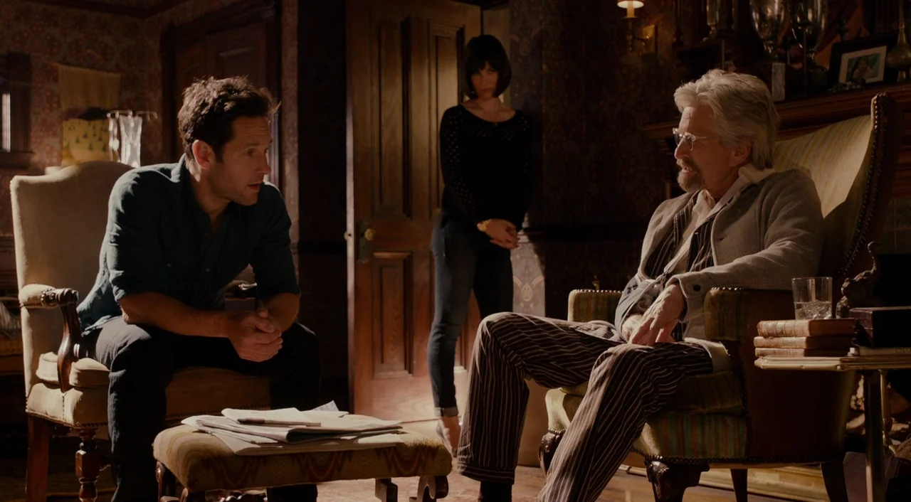 Ant-Man (2015) movie still: medium — A dark, wood-paneled living room features heavy floral wallpaper and ornate antique furniture. Two men sit…