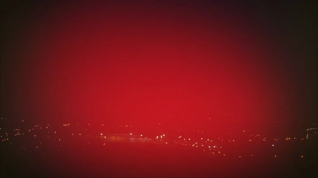 Red Road (2006) movie still: establishing — A night landscape is viewed from an elevated perspective overlooking a dimly lit city. Small clusters of…