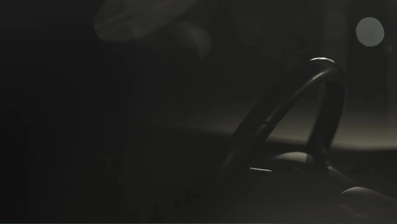 A Gift from God (2019) movie still: closeup — The interior of a car at night is mostly obscured by deep shadows. A black steering wheel is visible…