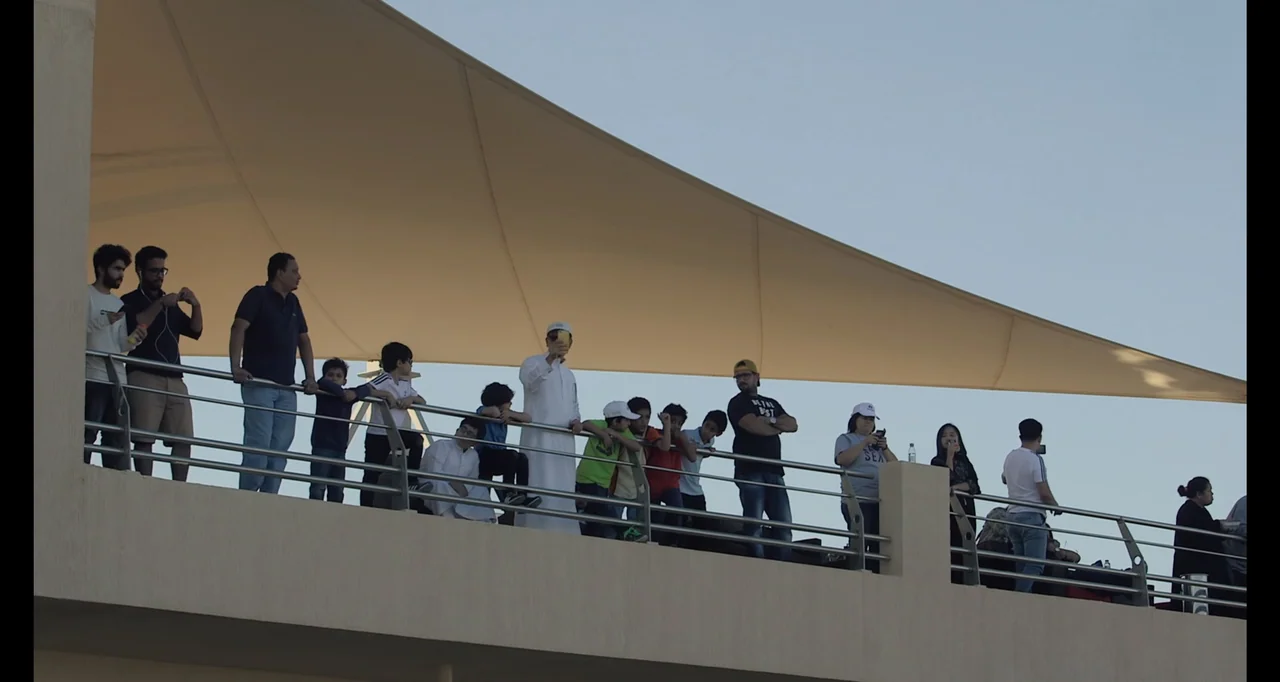 Saudi Women's Driving School (2019) movie still: wide — An outdoor observation deck features a long metal railing and a large tan sunshade. A…