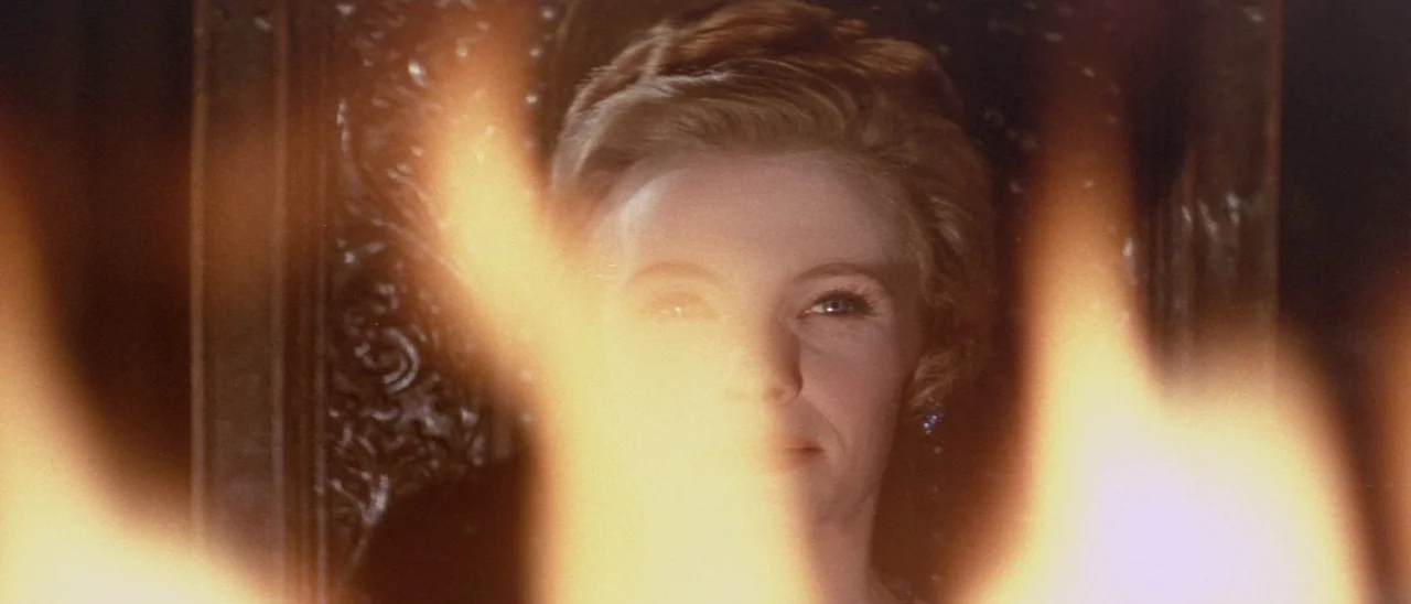 The Tomb of Ligeia (1964) movie still: closeup — A woman sits in a dark room with a patterned wooden chair behind her. Bright flickering flames in…