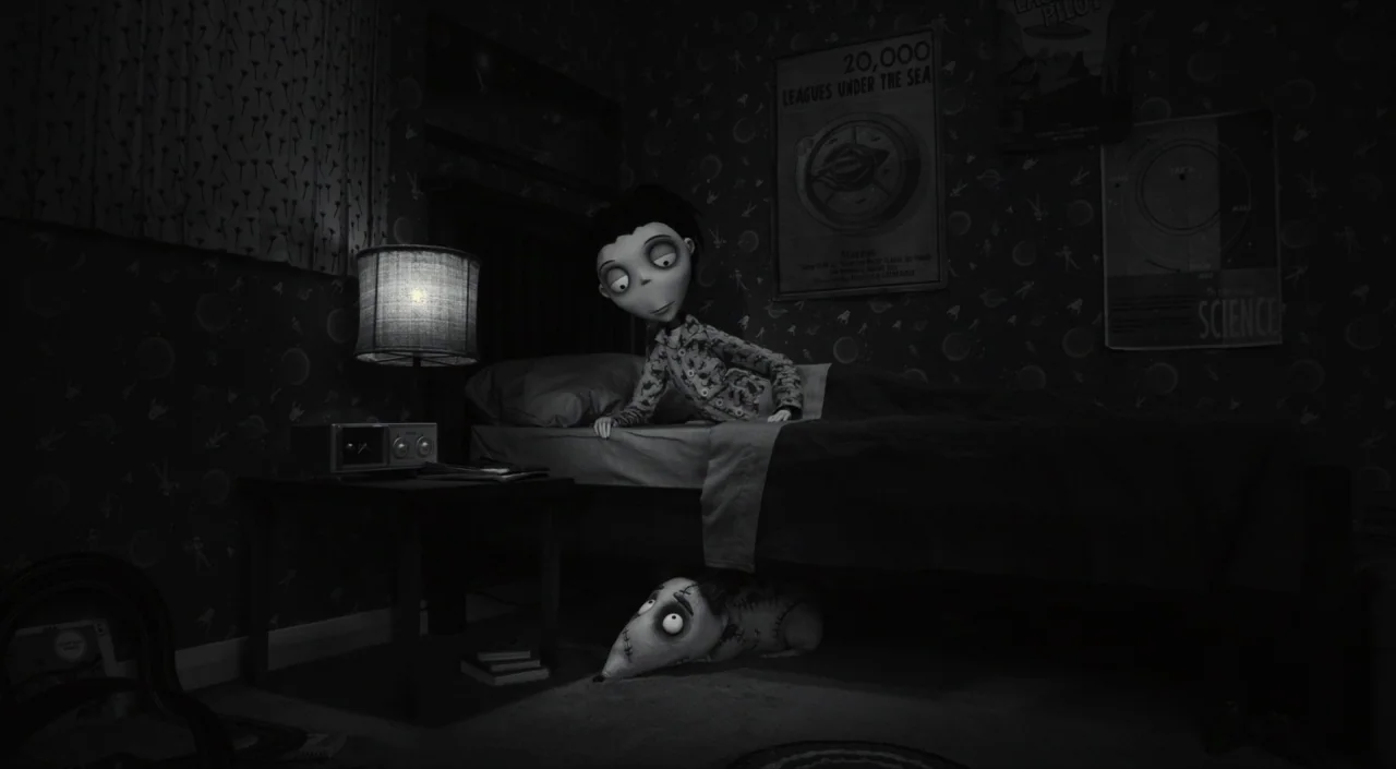 Frankenweenie (2012) movie still: medium — A dark, wallpapered room features a single bed and a small bedside table. A young boy in pajamas leans…