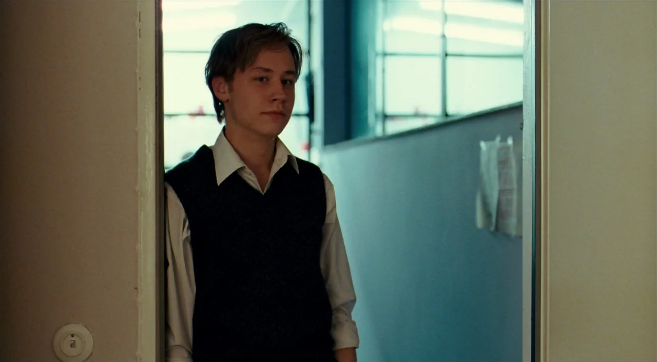 The Reader (2008) movie still: medium — A student stands in a doorway between a classroom and a brightly lit hallway. He leans against the door…