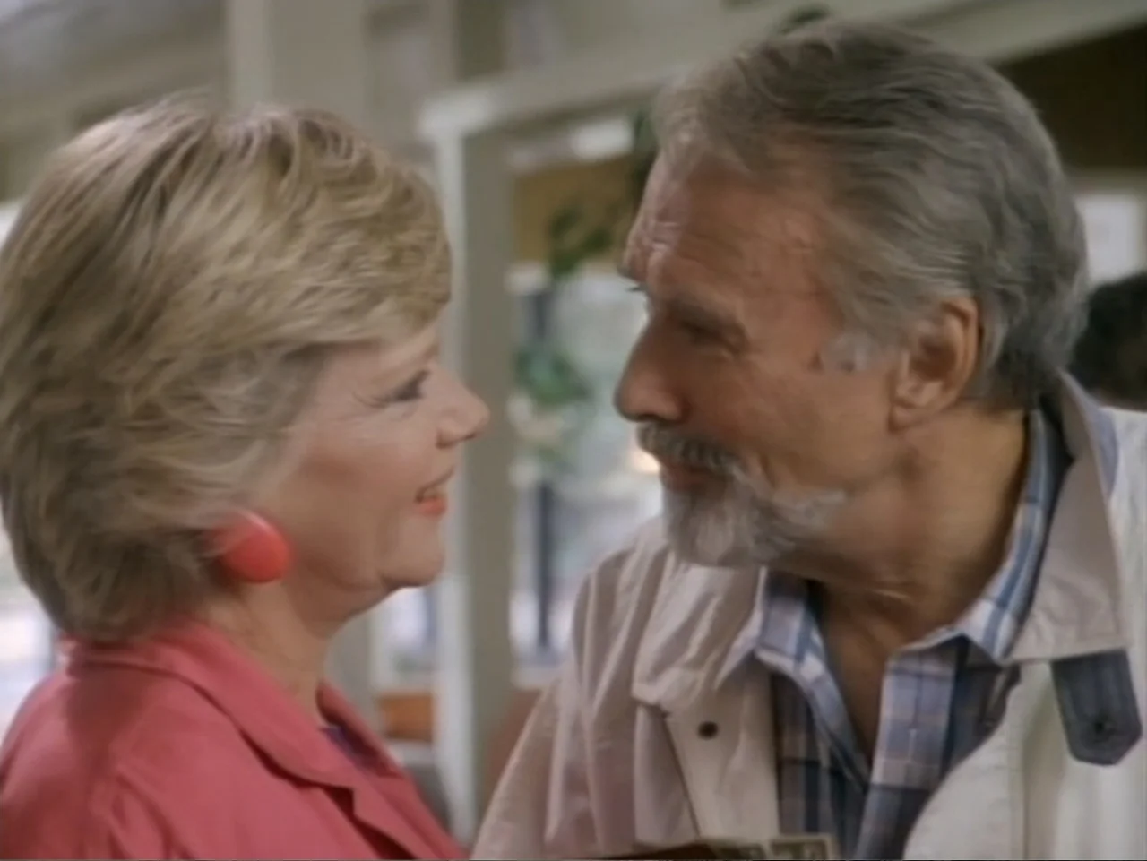 My First Love (1988) movie still: medium — A light-filled interior space with a booth seating structure in the background. An older woman and an…