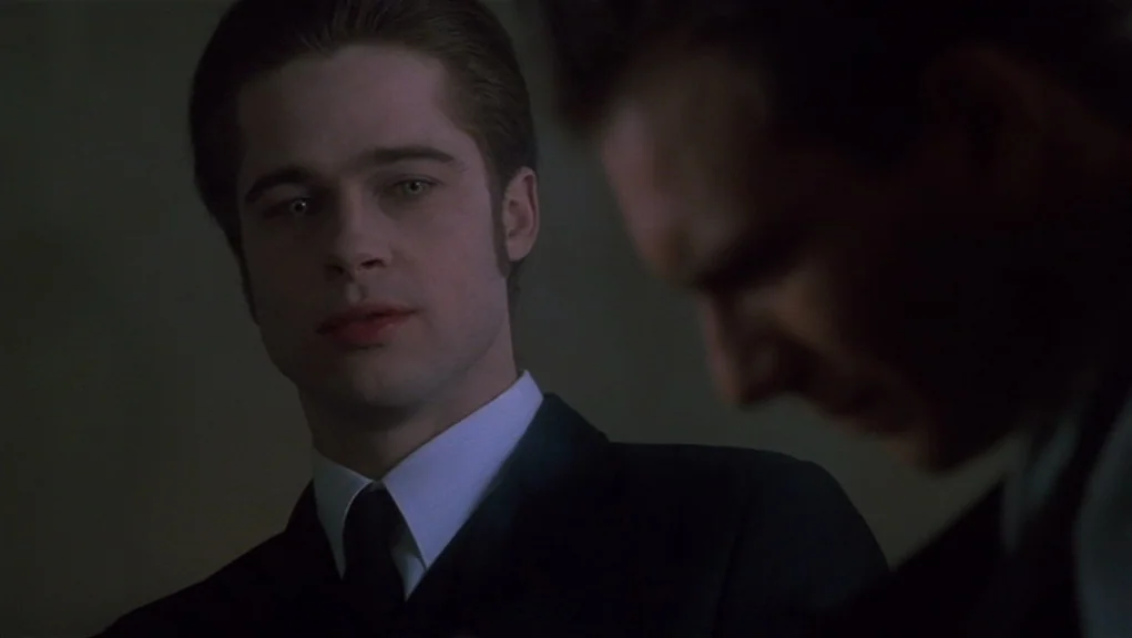 Interview With The Vampire movie still: medium — A dark indoor space with a man in a suit looking ahead. The man is captured in a medium…