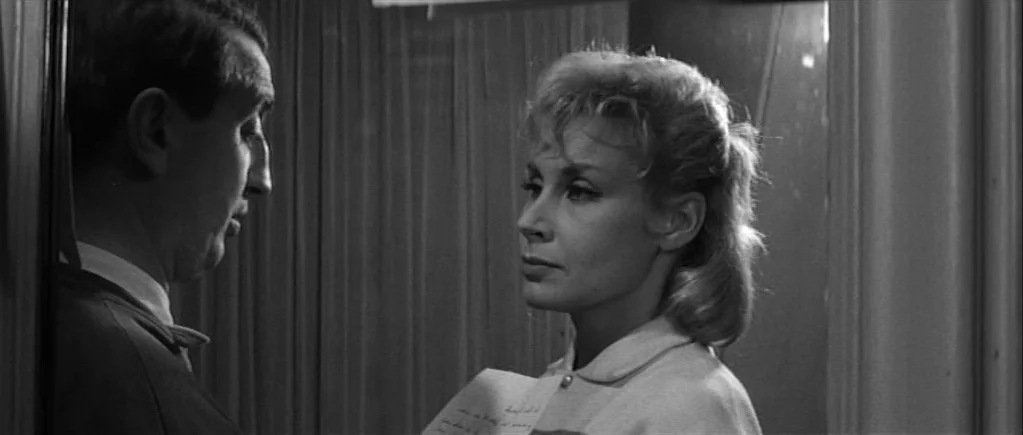 The 400 Blows (1959) movie still: medium — A dimly lit indoor space features a wall with vertical curtain panels behind people. A woman stands in…