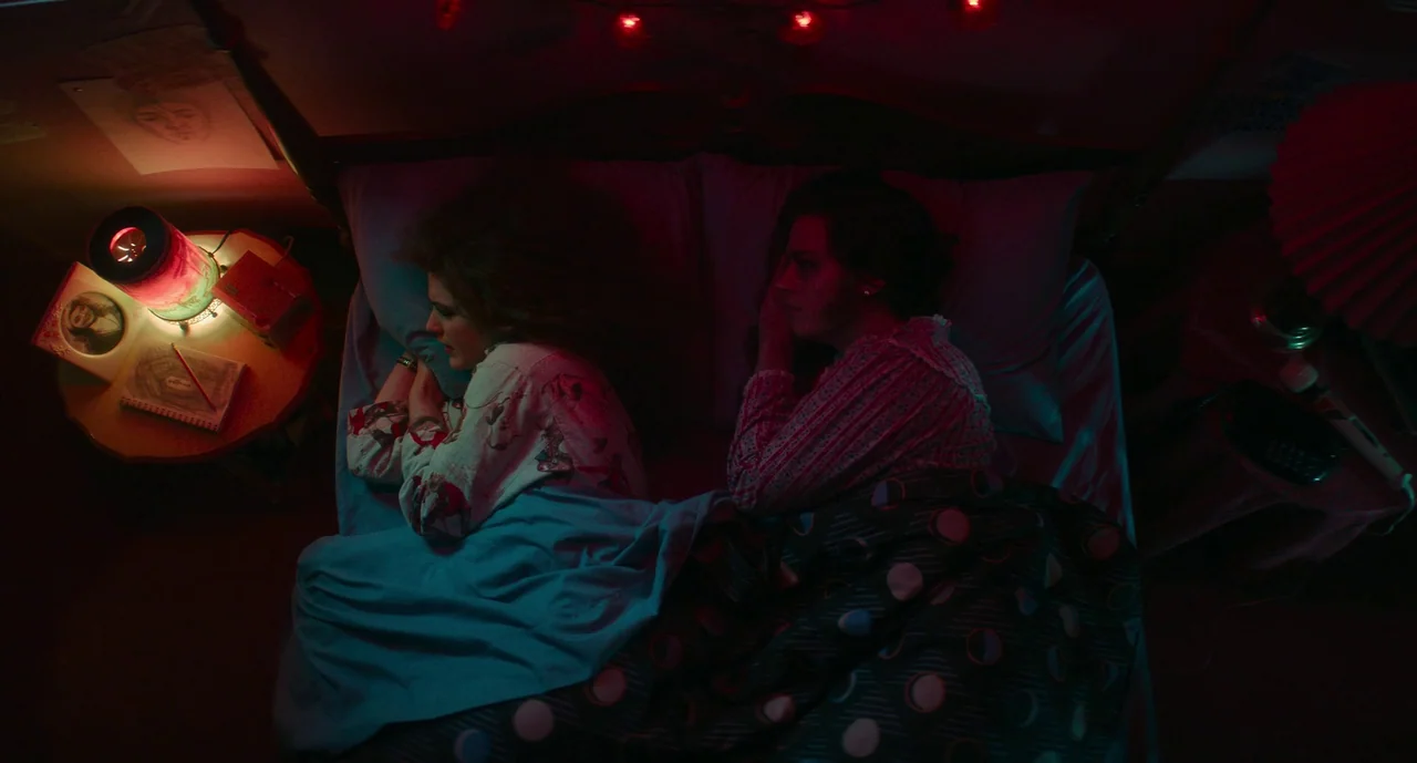 Lisa Frankenstein (2024) movie still: medium — A dark bedroom with two people lying in separate twin beds side by side. Each person faces away from…