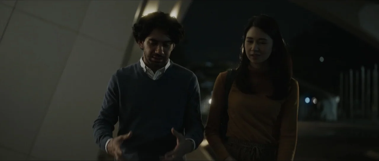 Innocent Vengeance (2023) movie still: medium — An urban walkway at night with angled concrete walls in the background. A man and a woman walk side…