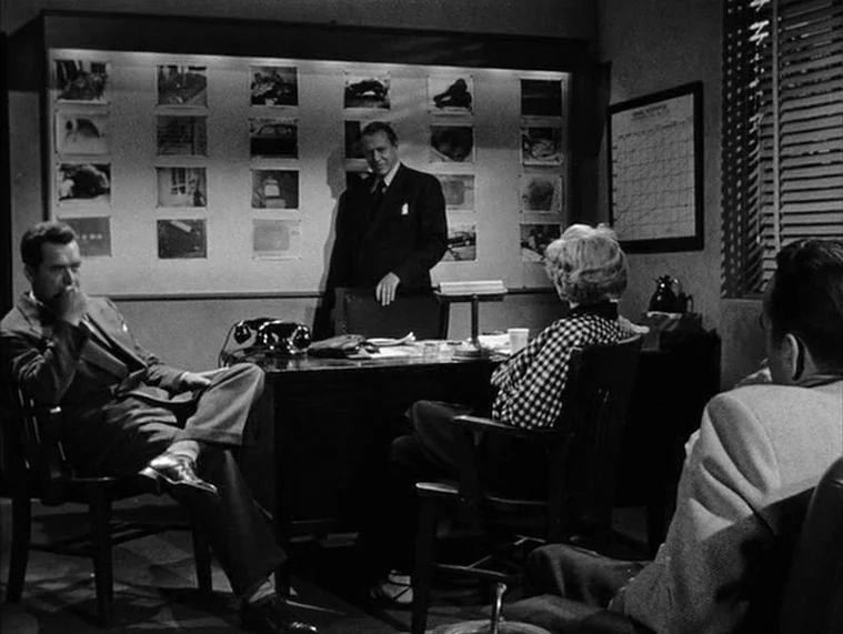 In a Lonely Place (1950) movie still: wide — An office features a large bulletin board covered with multiple crime scene photographs. Three people…