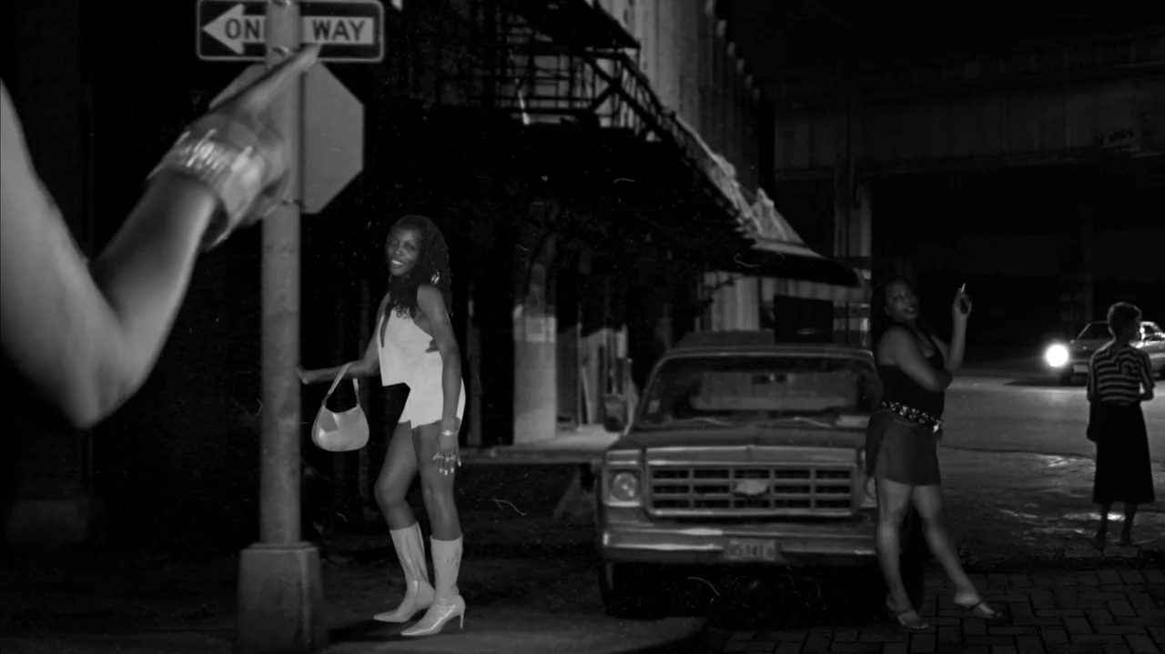 The Stroll (2023) movie still: medium — A dark urban corner at night features a parked vintage pickup truck. Two women stand near a street sign…