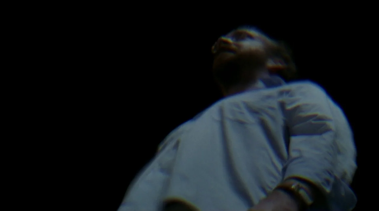 Lady in the Water (2006) movie still: medium — A man stands in darkness, captured from a low angle. He looks upward with his face partially…