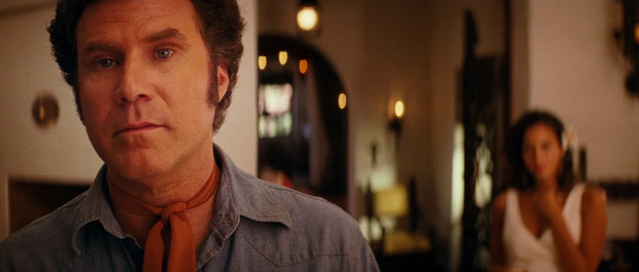 Casa De Mi Padre (2012) movie still: medium — A warmly lit Spanish-style villa interior features an arched doorway in the background. A man stands…