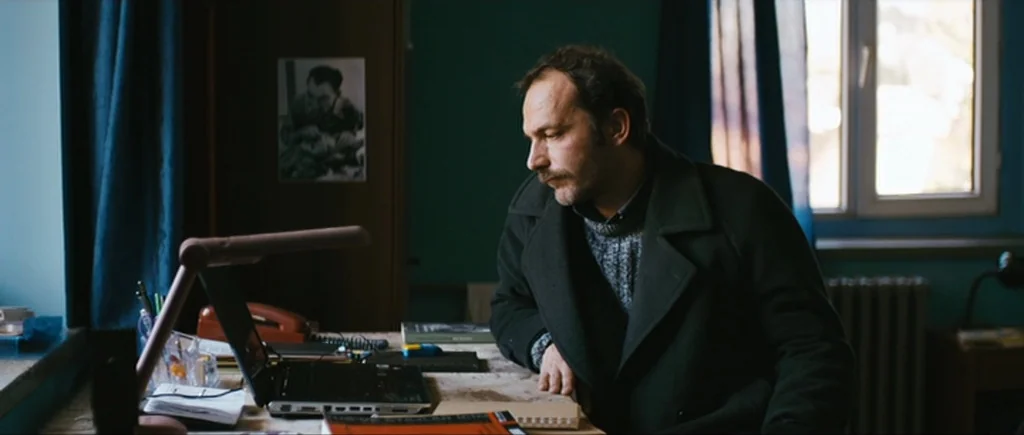 Once Upon a Time in Anatolia (2011) movie still: medium — A study room features dark teal walls and a desk cluttered with electronic equipment. A…