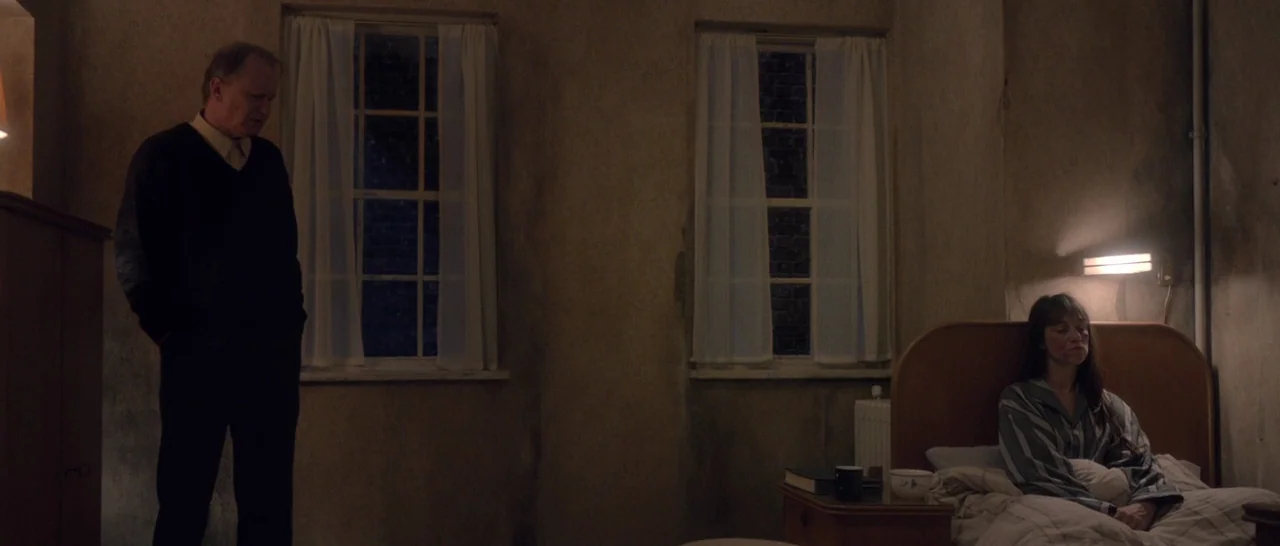 Nymphomaniac Vol 1 (2013) movie still: wide — A dimly lit room contains two windows with sheer curtains and a bed. An elderly man stands while a…