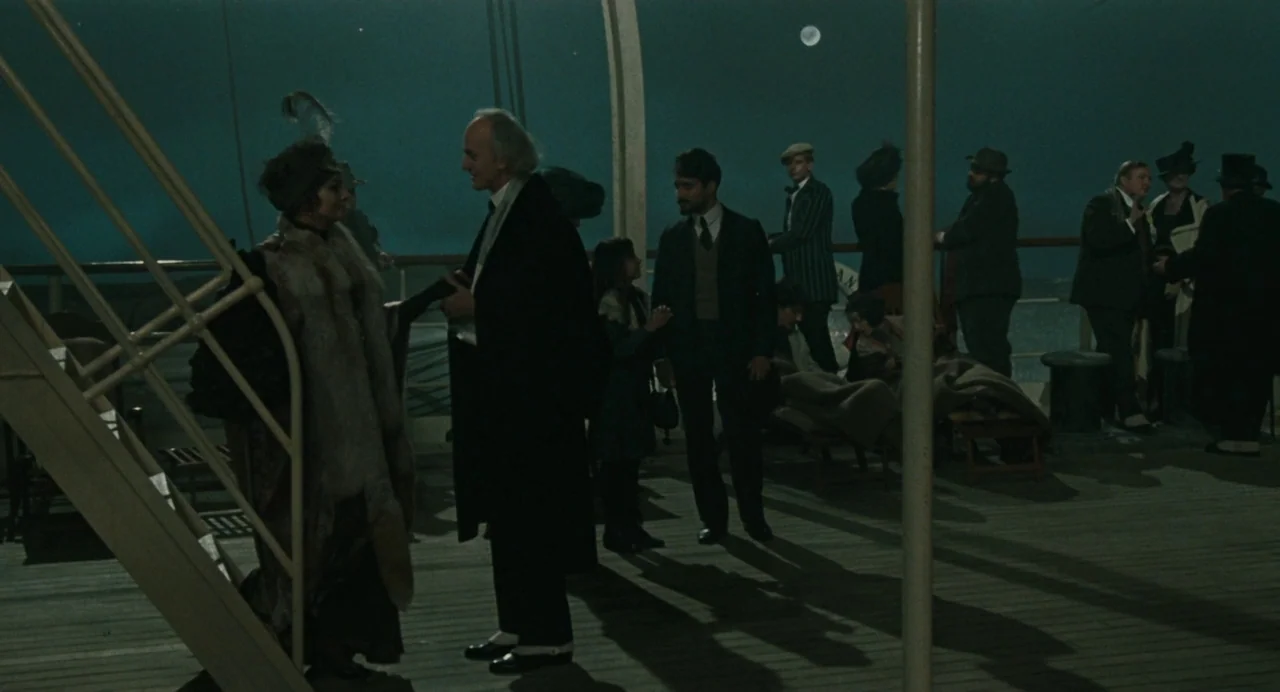 And The Ship Sails On (1983) movie still: wide — A steamship deck at night featuring several passengers gathered near the ship rail. A man and woman…