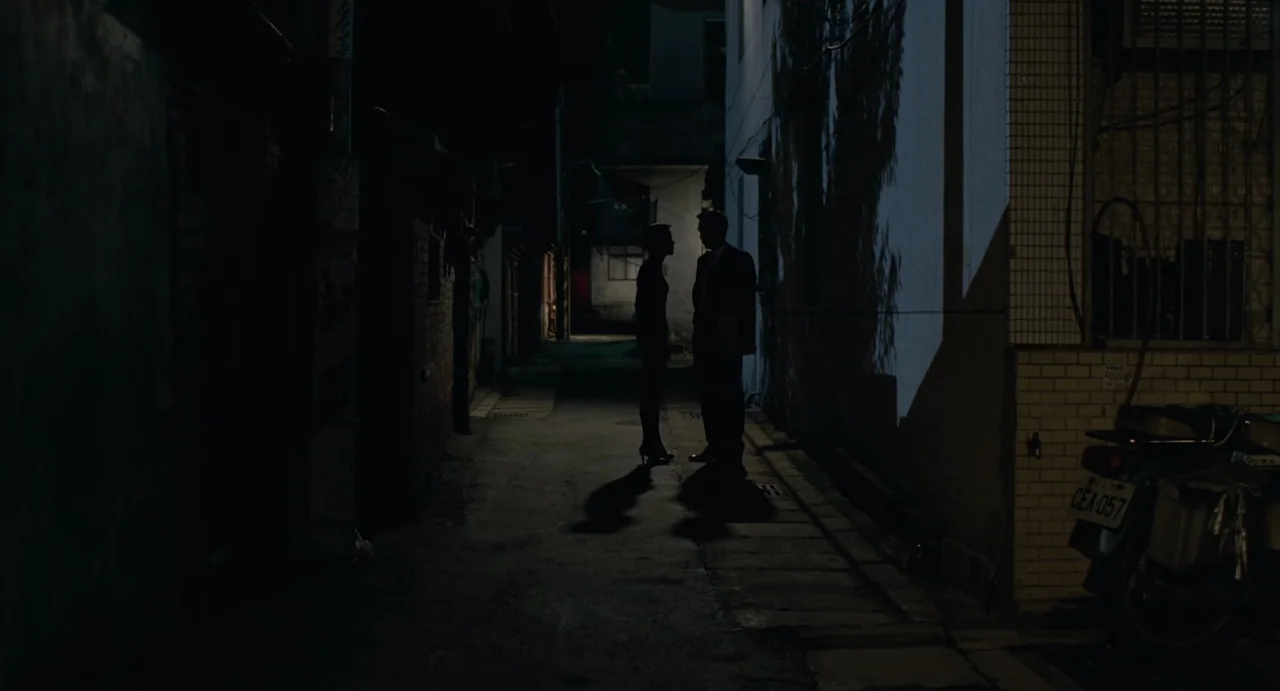 A Confucian Confusion (1994) movie still: wide — A narrow, dark urban alleyway features concrete walls and a parked scooter.