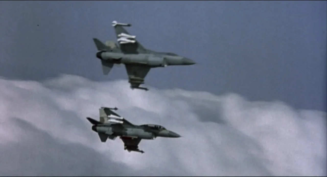Air Rage (2001) movie still: wide — Two grey fighter jets fly side by side above a thick layer of clouds. The sky is clear blue with sunlight…