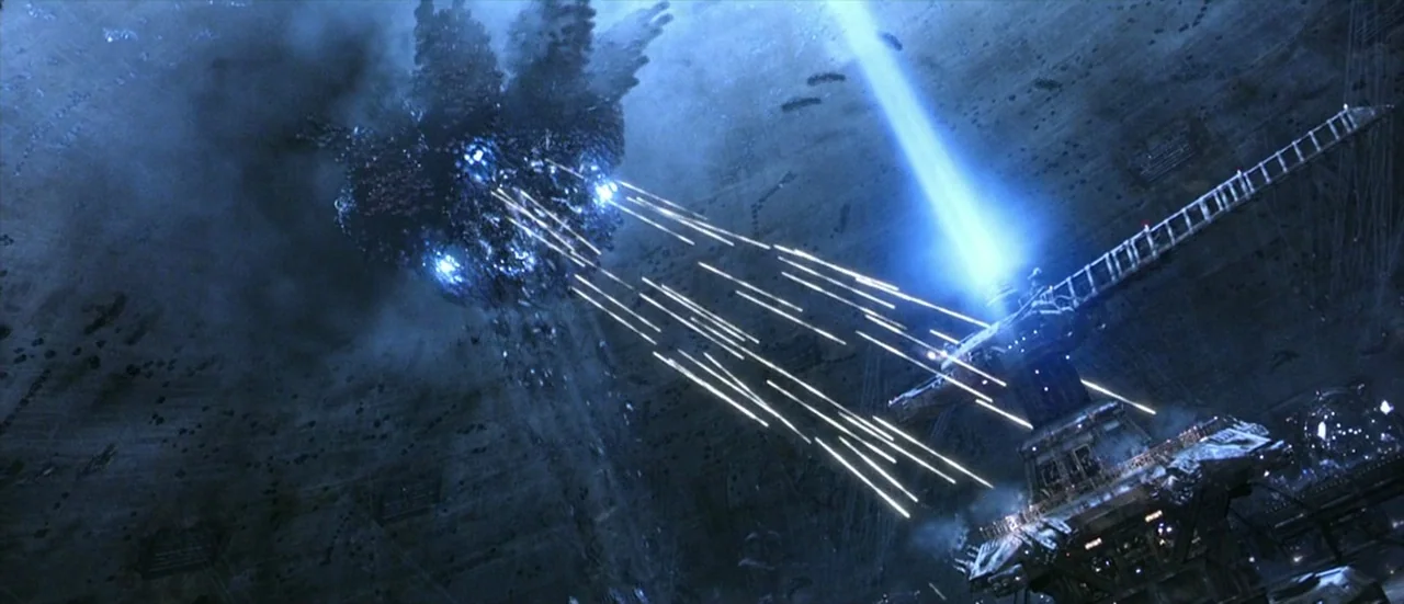 The Matrix Revolutions (2003) movie still: wide — A massive, dark, jagged spacecraft hovers above a complex technological installation on a cratered…