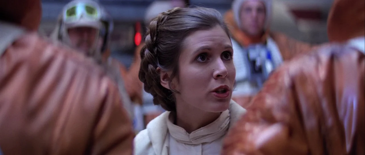The Empire Strikes Back (1980) movie still: medium — A crowded hangar bay features people wearing bright orange flight suits in the background. A…