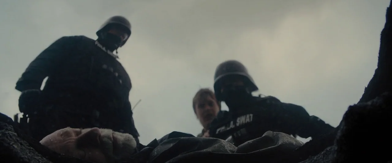 Glass (2019) movie still: medium — Tactical officers stand over an unconscious man in a dimly lit, debris-filled area. The scene is shot from a low…